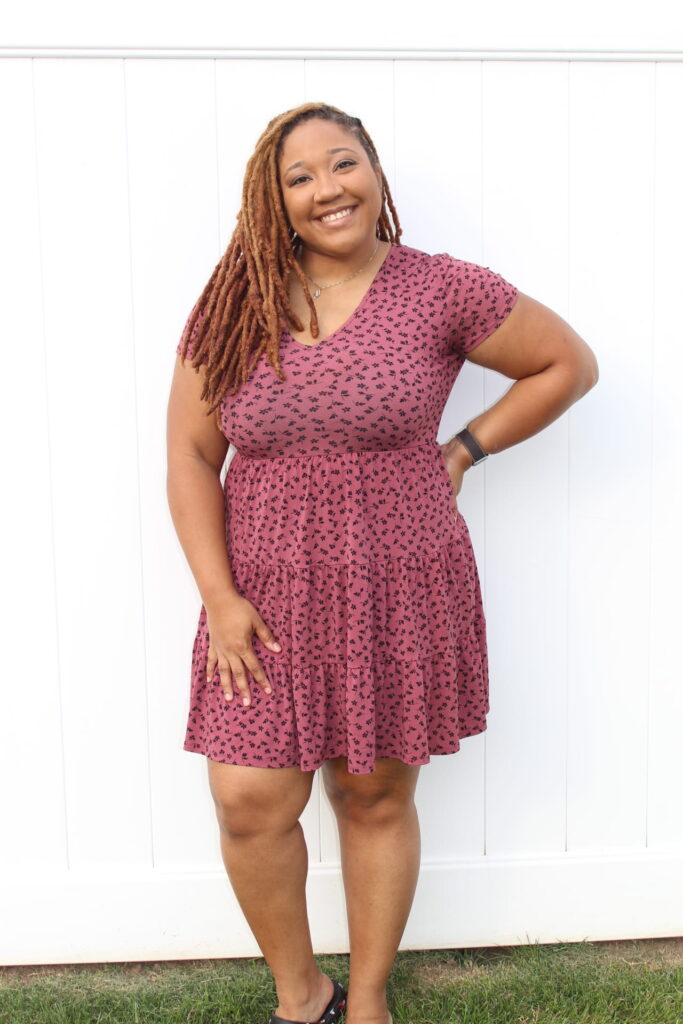 tracy standing with hand on hip in a pink dress